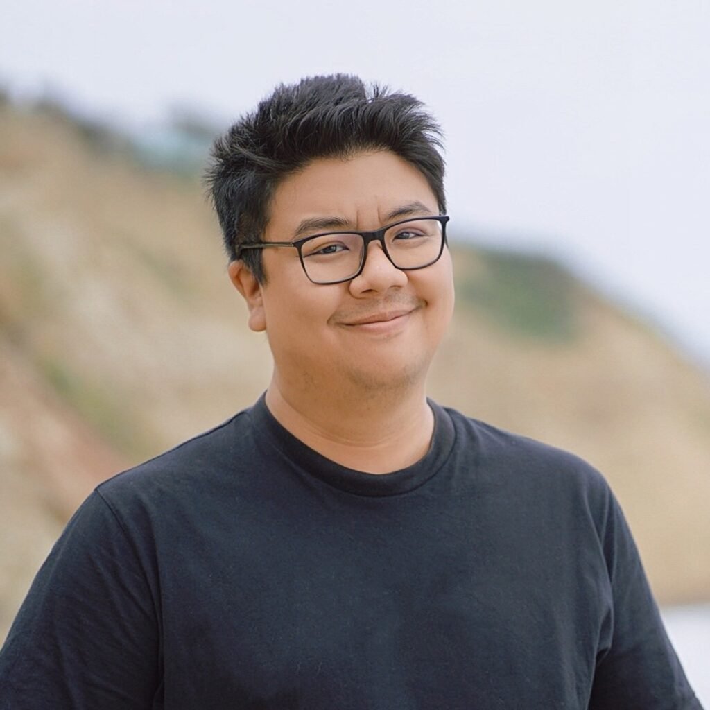 Picture of Tiankai Feng wearing a black t-shirt and glasses, smiling at the camera.